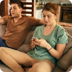Two young people relax on couch, girl scrolls her cell phone. 